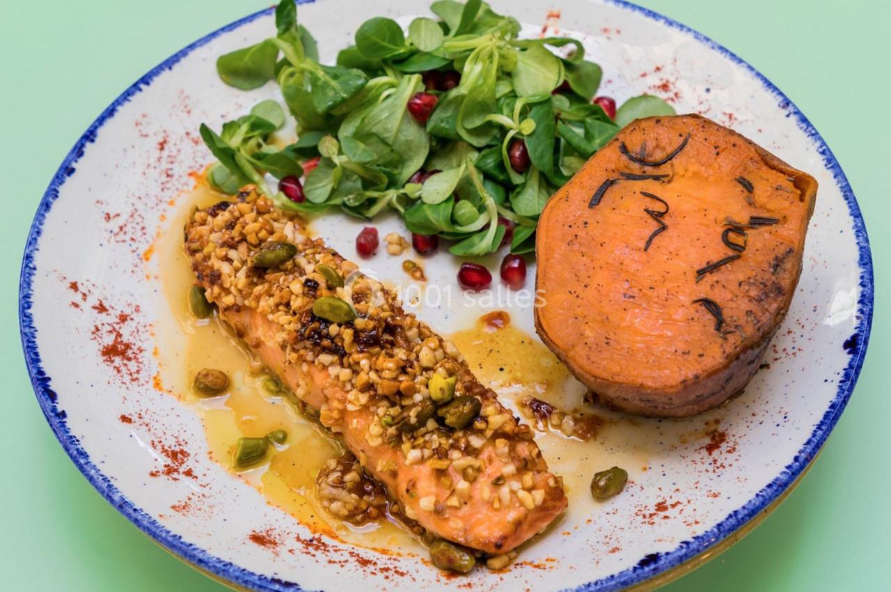 Filet de saumon aux pistaches, patate douce grillée et mâche garnie de graines de grenade sur une assiette.