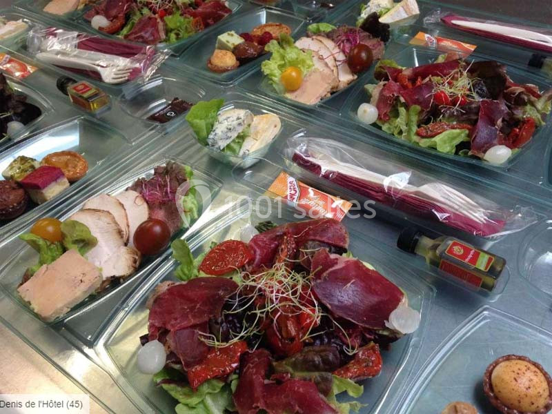 Plateaux-repas composés de charcuterie, salade, fromage, pain et condiments, présentés dans des emballages individuels.