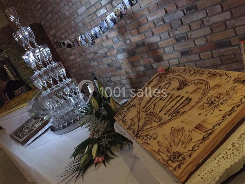 Tour de coupes en verre et décoration florale sur une table, avec une planche gravée au motif de cœur.