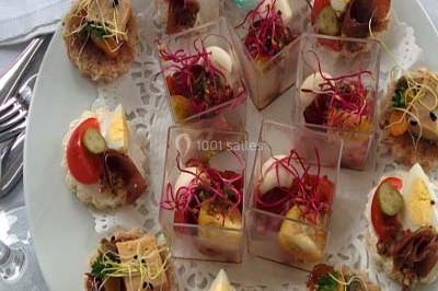 Salle de réception décorée avec des tables dressées, nappes blanches et touches de bleu, prête pour un événement.