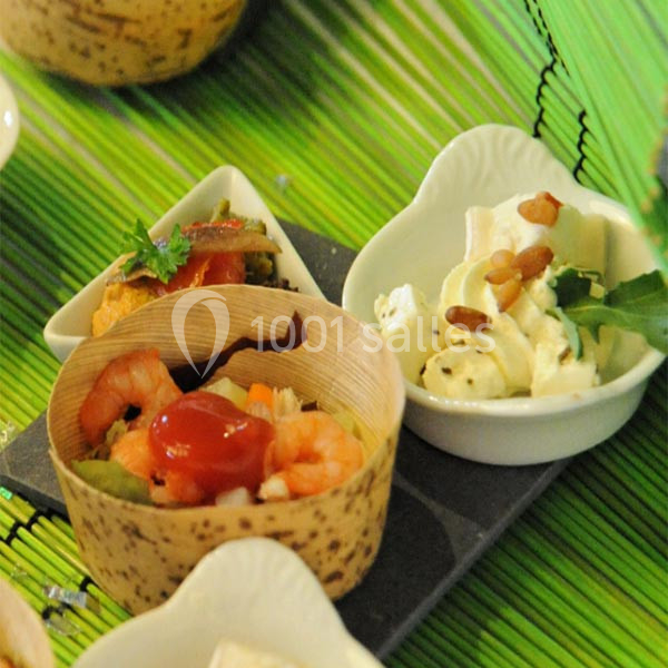 Assortiment de verrines et amuse-bouches avec crevettes, légumes et fromage, présenté sur un fond vert.