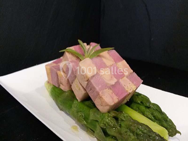 Terrine en damier servie sur un lit d'asperges vertes, présentée sur une assiette blanche.