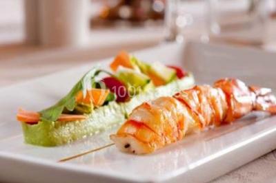 Boule panée garnie de pinces de crabe, posée sur une tranche de gratin, décorée d'aneth sur une assiette blanche.