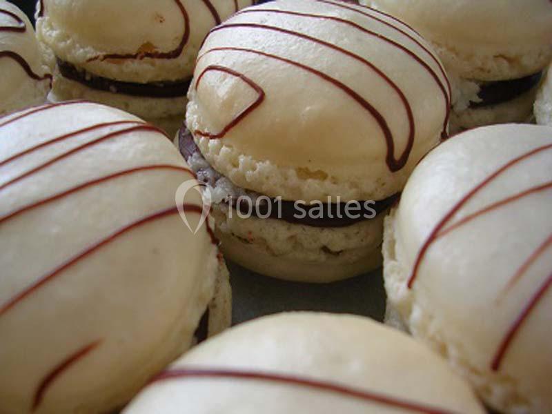 Macarons blancs garnis de chocolat, décorés de fines lignes de glaçage au chocolat sur le dessus.