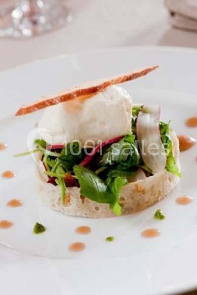 Assiette de salade garnie de légumes frais, fromage, croustillant et décorée de petites touches de sauce.