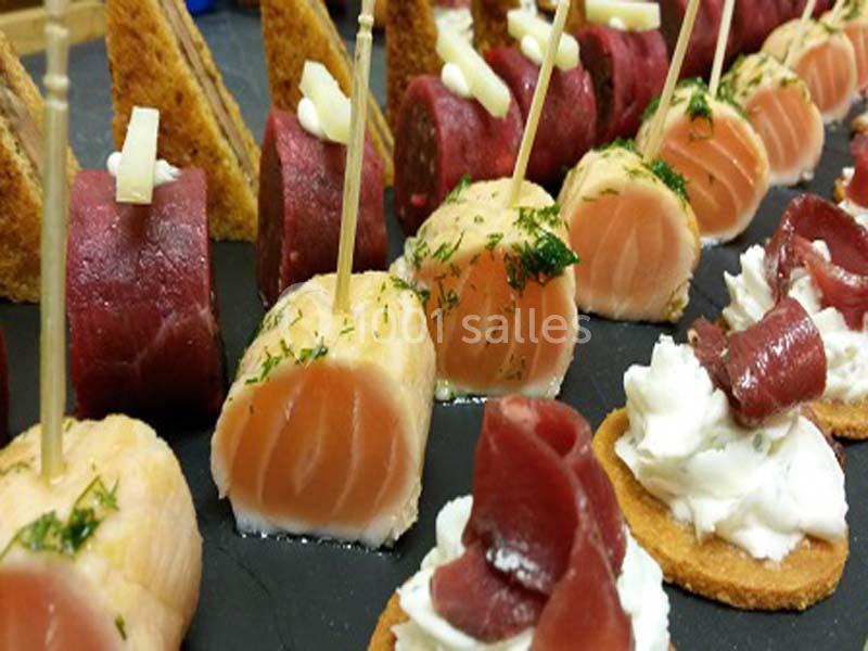 Assortiment de bouchées apéritives avec saumon, viande séchée, fromage et pain sur un plateau.