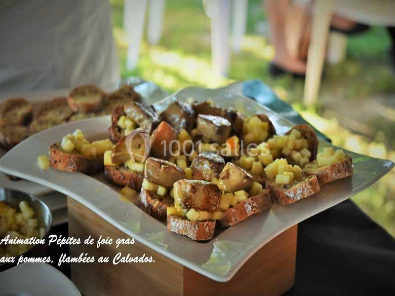 Tranches de pain garnies de foie gras, dés de pommes et flambées au Calvados, présentées sur un plateau.