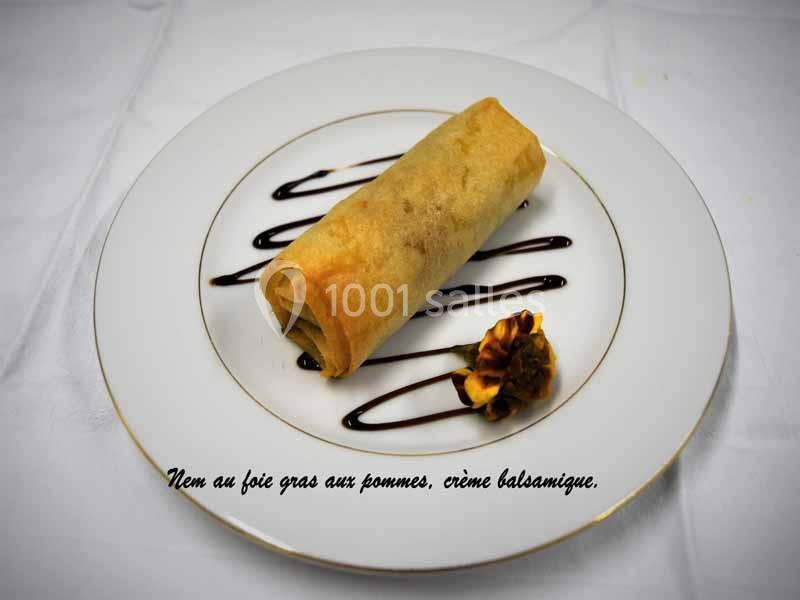 Nem au foie gras et pommes, dressé sur une assiette avec crème balsamique et décoration florale comestible.