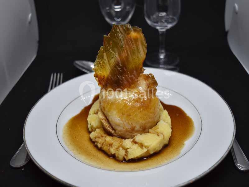 Plat gastronomique composé d'une volaille rôtie sur purée, nappée de sauce, avec une décoration croustillante.