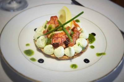 Plateau de bouchées variées comprenant mini-sandwichs, brochettes de crevettes, œufs de caille et desserts colorés.