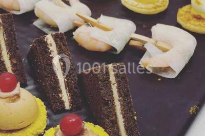 Plateau de bouchées variées comprenant mini-sandwichs, brochettes de crevettes, œufs de caille et desserts colorés.