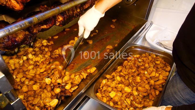 Préparation de pommes de terre rôties dans un four professionnel, avec une personne les transférant dans un plat en inox.