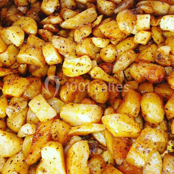 Pommes de terre rôties dorées, assaisonnées d'herbes et d'épices, disposées en grande quantité.