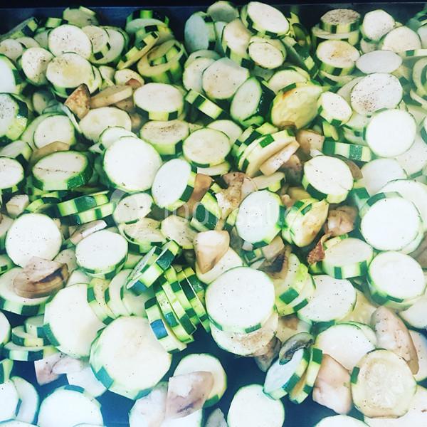 Tranches de courgettes crues mélangées à des morceaux de champignons, disposées sur une surface plate.