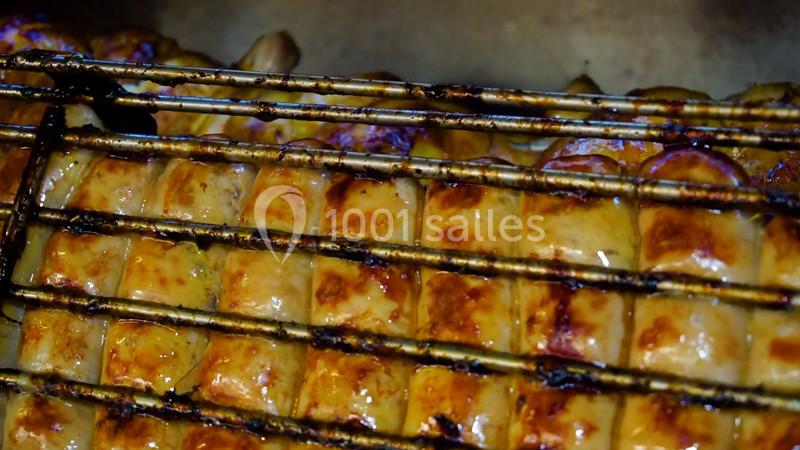 Saucisses grillées dorées sur un gril métallique, légèrement caramélisées par la cuisson.