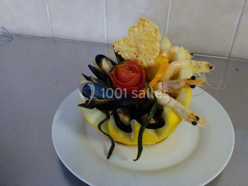 Assiette de fruits de mer avec moules, crevettes et décoration de légumes dans une coque de melon.