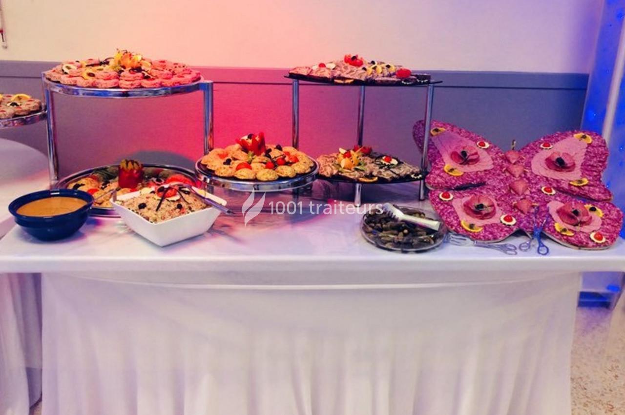 Buffet décoratif avec plats variés, salades, sauces et présentation en forme de papillon sur une table blanche.