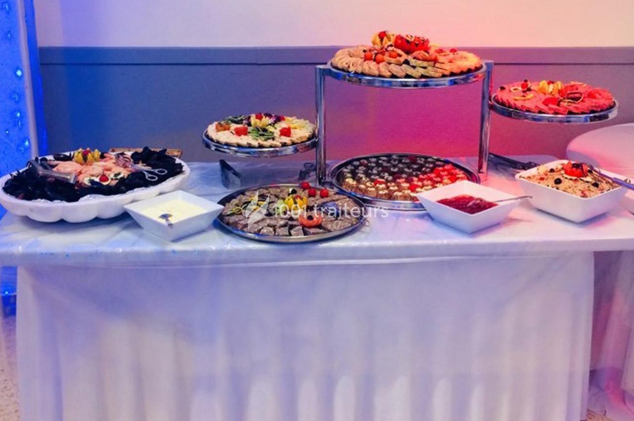 Table de buffet avec divers plats, notamment des plateaux de desserts, fruits, sauces et amuse-bouches.