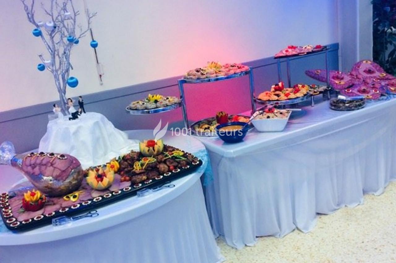 Buffet décoré avec des plats variés, incluant des fruits sculptés, des viandes et des desserts, sur des tables drapées de…