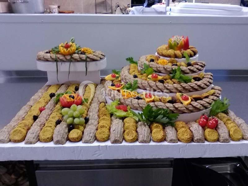 Plateau décoratif de pâtisseries et biscuits disposés en spirale avec des garnitures de fruits et légumes sculptés.