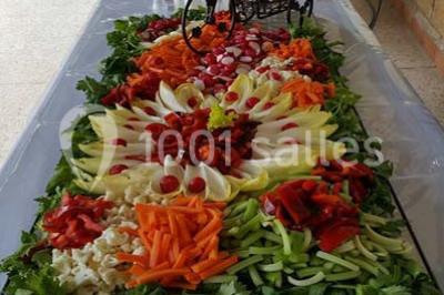 Buffet décoré avec des plats variés, incluant des fruits sculptés, des viandes et des desserts, sur des tables drapées de…