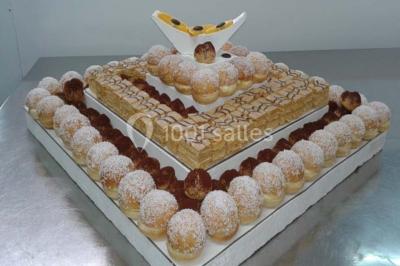 Buffet décoré avec des plats variés, incluant des fruits sculptés, des viandes et des desserts, sur des tables drapées de…