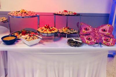 Buffet décoré avec des plats variés, incluant des fruits sculptés, des viandes et des desserts, sur des tables drapées de…