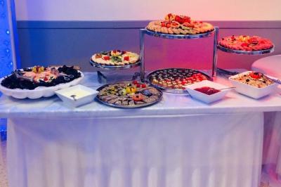 Buffet décoré avec des plats variés, incluant des fruits sculptés, des viandes et des desserts, sur des tables drapées de…