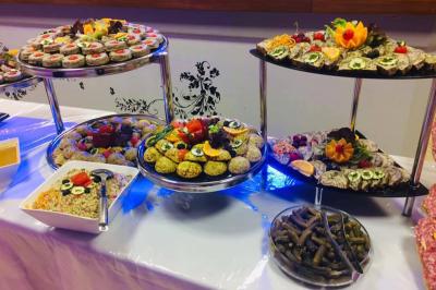 Buffet décoré avec des plats variés, incluant des fruits sculptés, des viandes et des desserts, sur des tables drapées de…