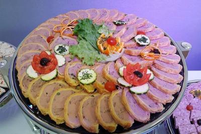 Buffet décoré avec des plats variés, incluant des fruits sculptés, des viandes et des desserts, sur des tables drapées de…