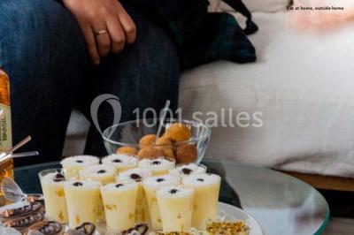 Salle de réception décorée avec des tables alignées, nappes blanches, chaises pliantes et ornements suspendus.