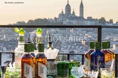 Salle de réception décorée avec des tables alignées, nappes blanches, chaises pliantes et ornements suspendus.