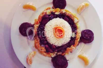 Salle de réception décorée avec des tables alignées, nappes blanches, chaises pliantes et ornements suspendus.