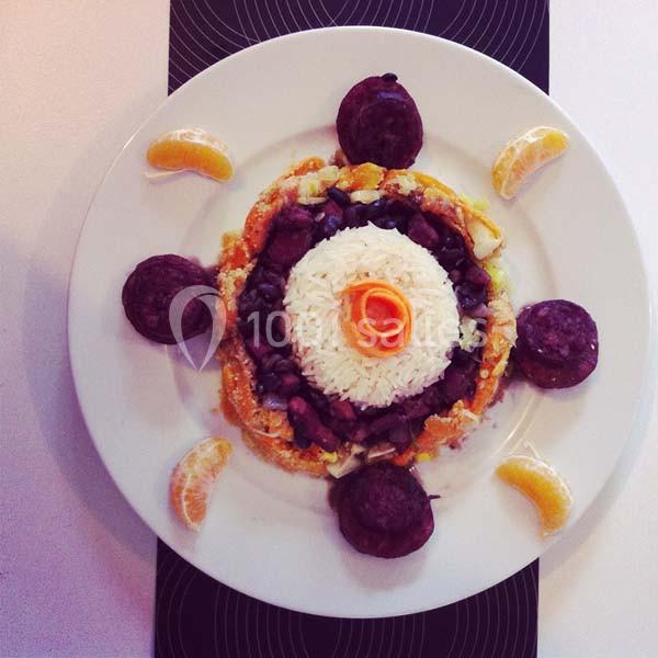 Assiette garnie de riz, légumes, morceaux de viande, rondelles de boudin noir et quartiers de mandarine.