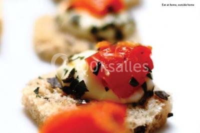 Salle de réception décorée avec des tables alignées, nappes blanches, chaises pliantes et ornements suspendus.