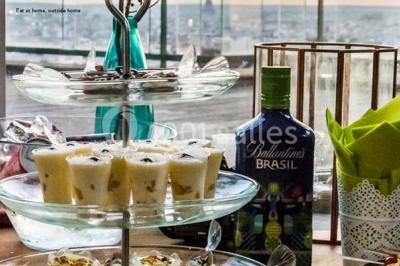 Salle de réception décorée avec des tables alignées, nappes blanches, chaises pliantes et ornements suspendus.