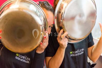 Salle de réception décorée avec des tables alignées, nappes blanches, chaises pliantes et ornements suspendus.