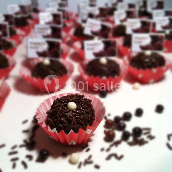 Truffe au chocolat décorée de vermicelles et d'une perle blanche, présentée dans une caissette rouge.