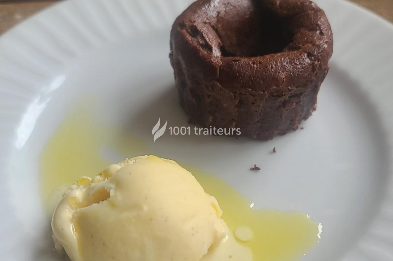 Moelleux au chocolat accompagné d'une boule de glace à la vanille sur une assiette blanche.