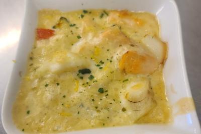 Plat composé d'une cuisse de volaille nappée de sauce, pommes de terre rôties et roulé de légumes en forme de fleur.