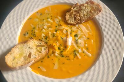 Plat composé d'une cuisse de volaille nappée de sauce, pommes de terre rôties et roulé de légumes en forme de fleur.