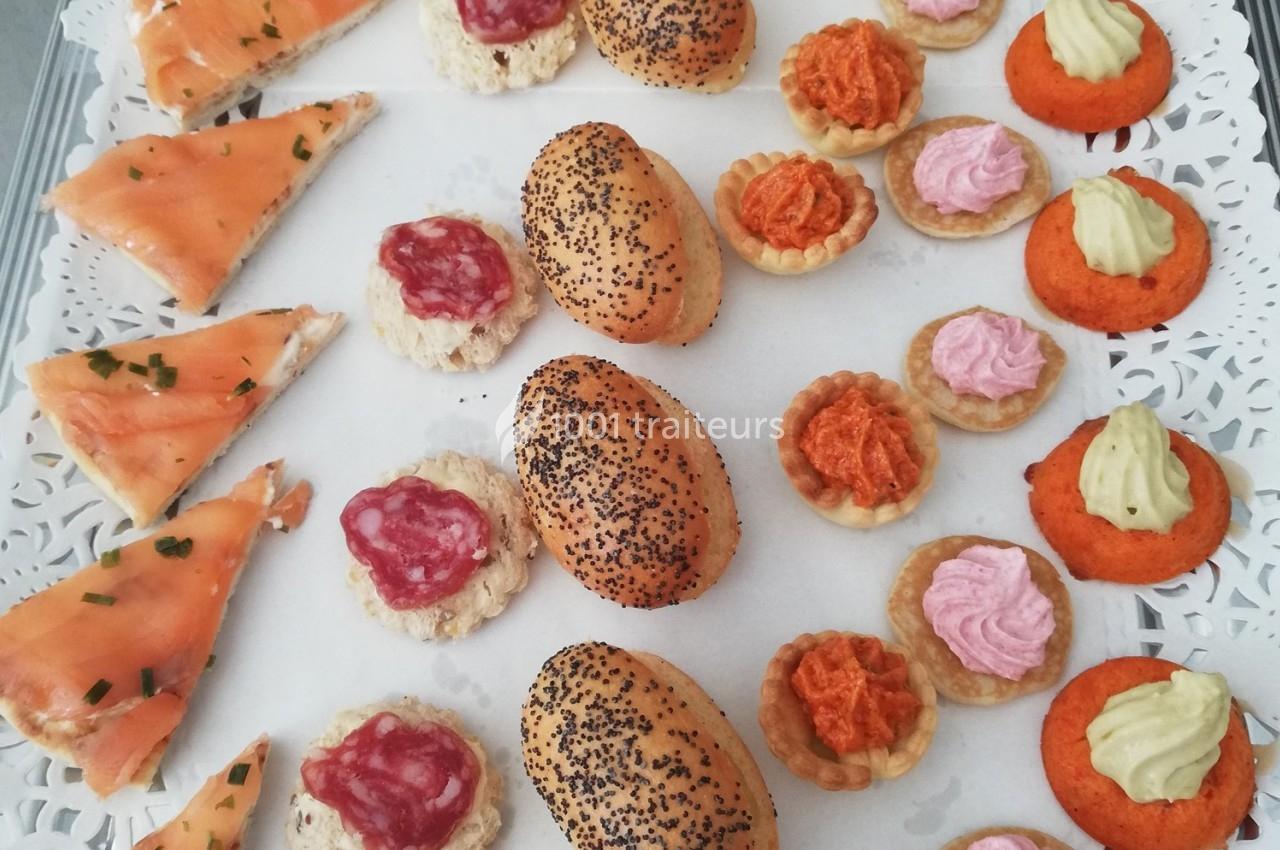 Plateau de petits fours variés comprenant saumon, tartelettes garnies et pains aux graines de pavot.