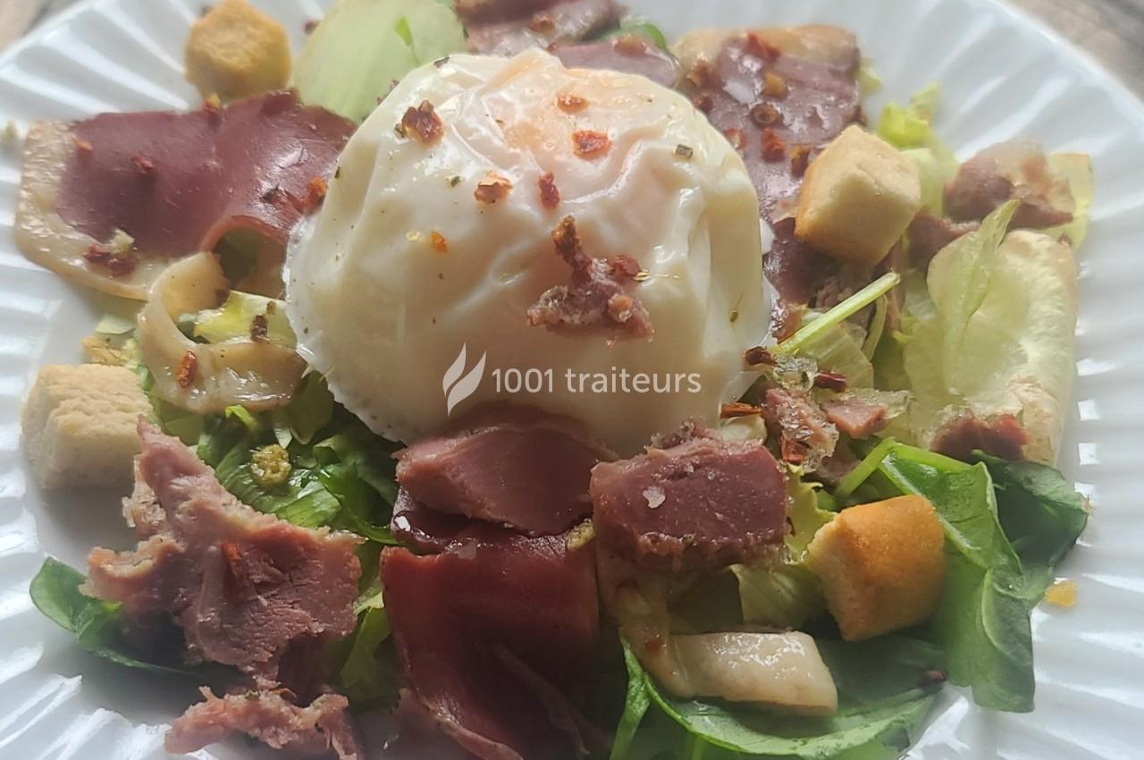 Salade composée avec œuf poché, magret de canard, croûtons, champignons et feuilles de salade verte.