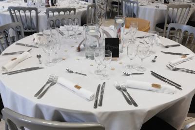 Table avec une pièce montée, des bouteilles de champagne, une pyramide de flûtes et une pile d'assiettes blanches.