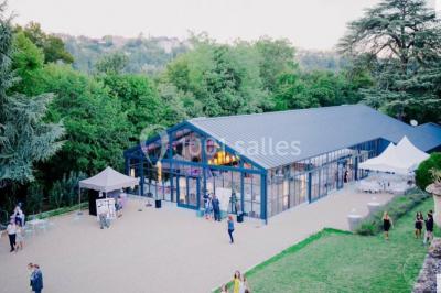 Un couple de mariés danse sous des lumières suspendues, entouré d'invités célébrant avec des serviettes levées.