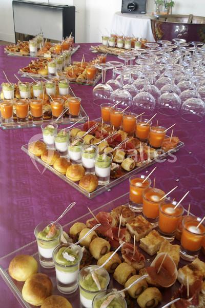 Buffet avec verrines, amuse-bouches variés et verres à pied disposés sur une nappe violette.