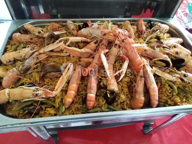 Plat de paella aux fruits de mer avec crevettes, langoustines, moules et légumes, présenté dans un grand plat en inox.