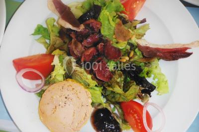Gâteau décoré de tranches de fraises disposées en cercle avec une fraise entière et une feuille de menthe au centre.