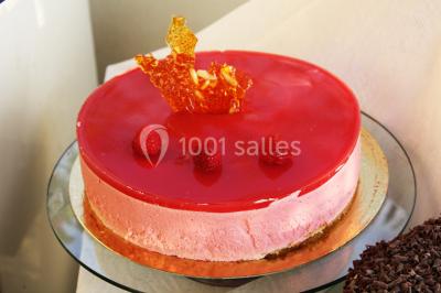 Gâteau décoré de tranches de fraises disposées en cercle avec une fraise entière et une feuille de menthe au centre.