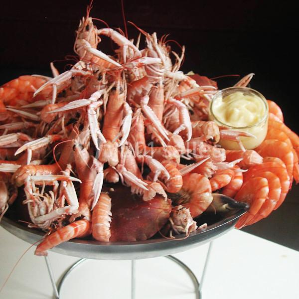 Plateau de fruits de mer avec langoustines, crevettes et sauce mayonnaise dans une coupelle en verre.